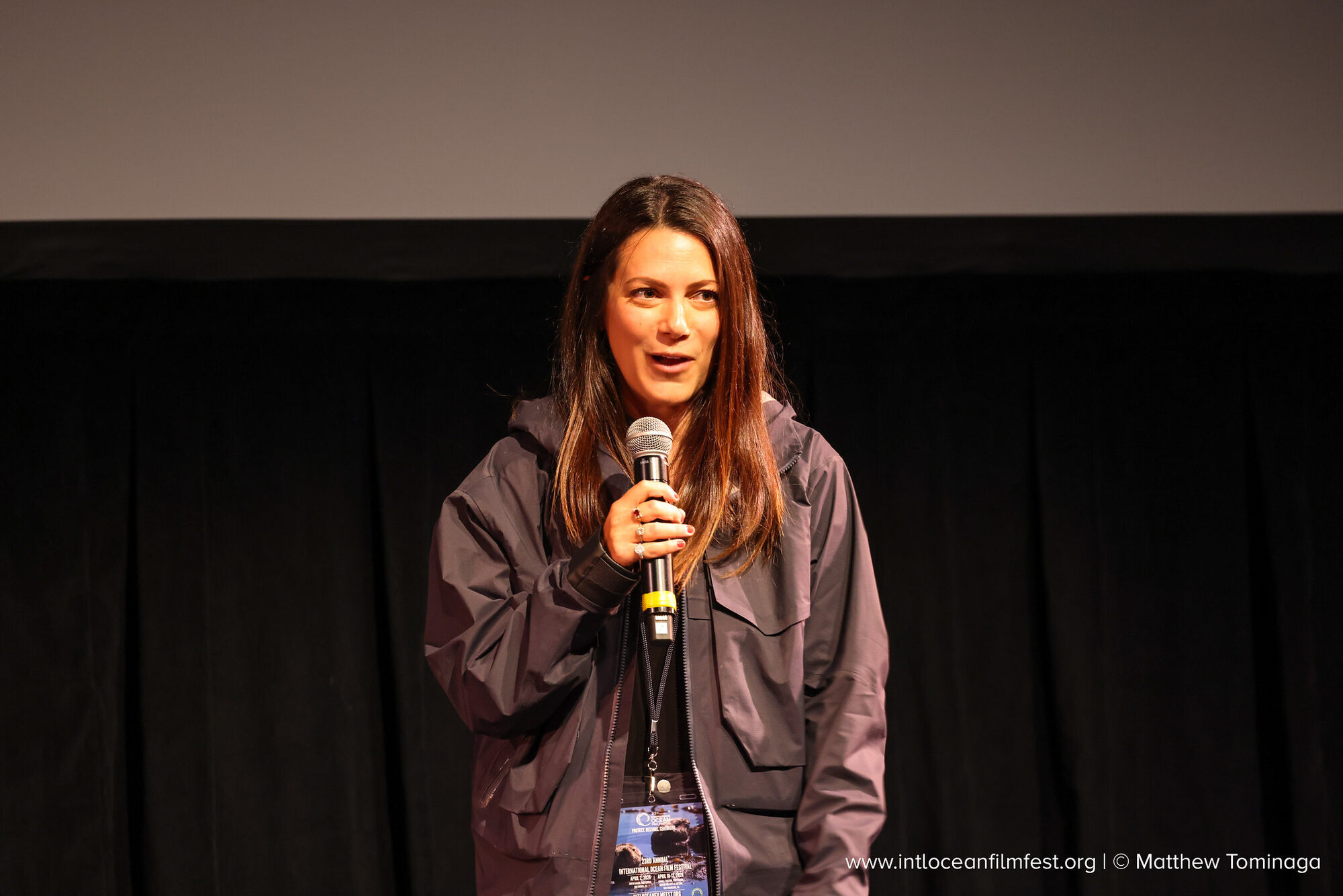 Andi Cross speaking into a microphone on stage at the International Ocean Film Festival