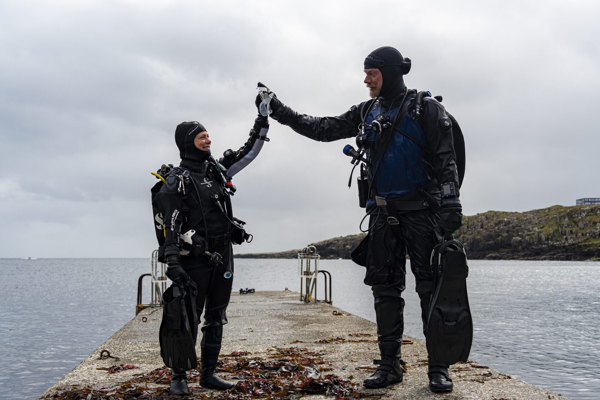 Diving team high-five moment in Faroe Islands, celebrating successful dive expedition